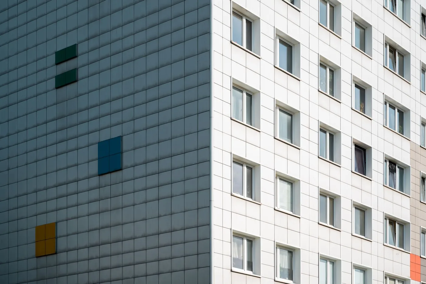 Fasáda paneláku s barevnými čtvercovými akcenty
