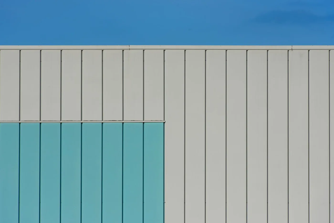 Detail světle šedé fasády budovy s oblohou