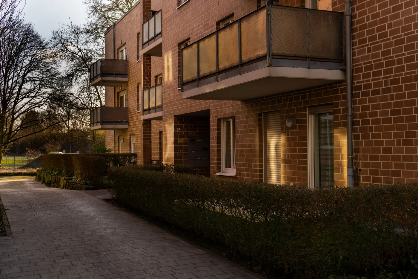 Cihlový bytový dům s balkony a keři