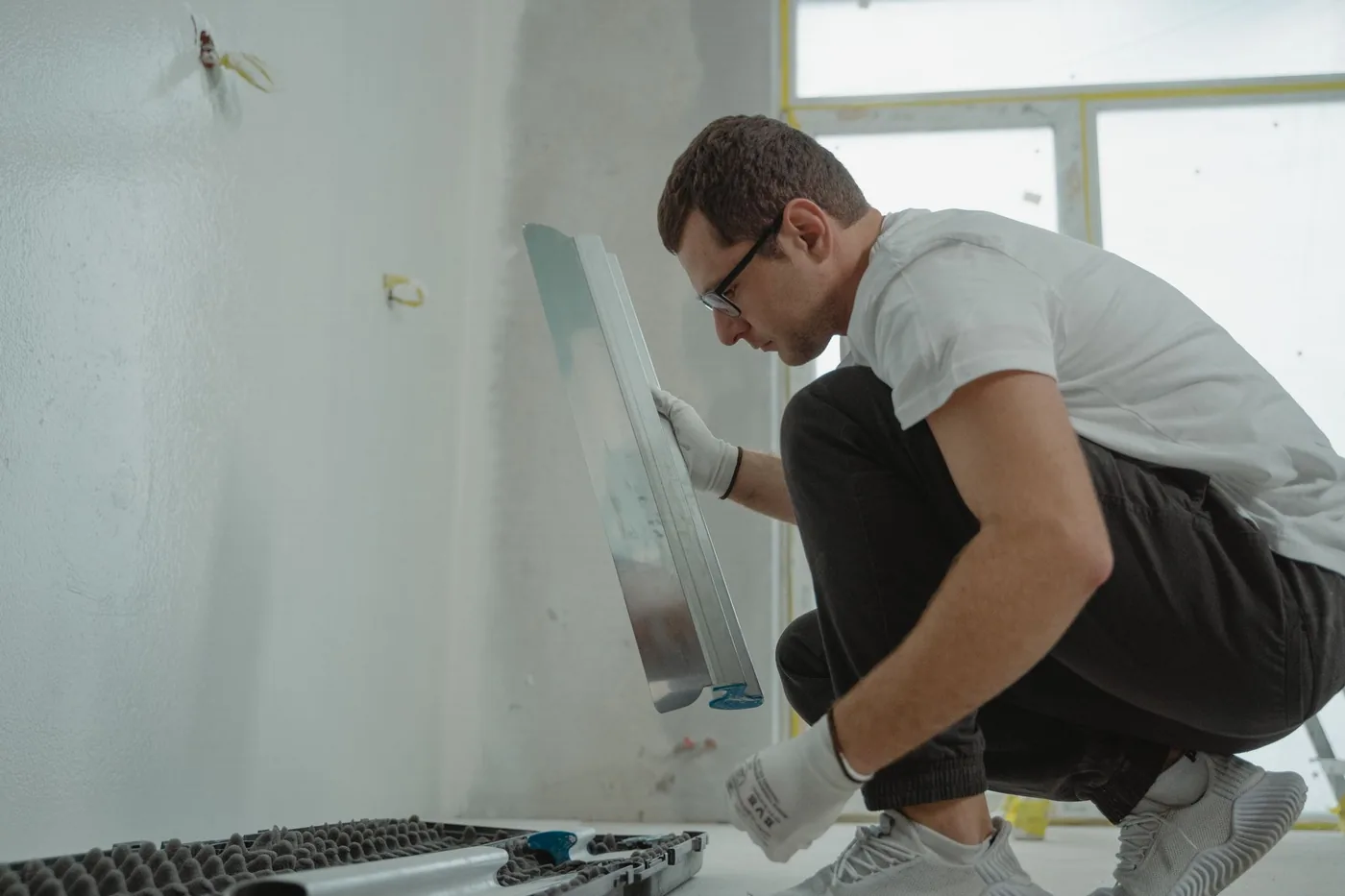 Muž pracuje s hladítkem u stěny místnosti