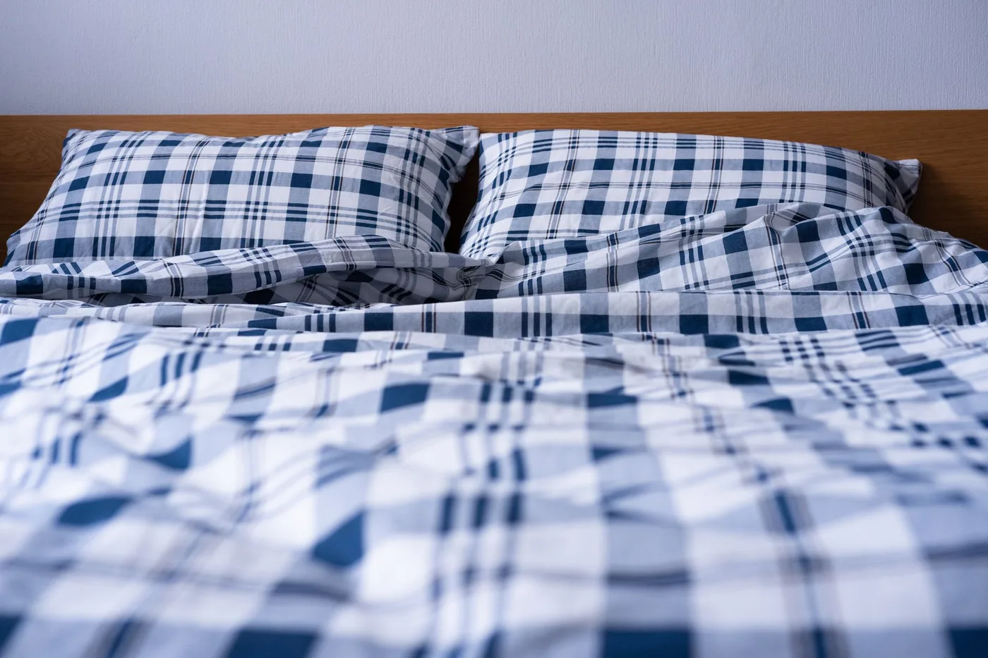Dvojlůžko s kostkovaným povlečením v ložnici