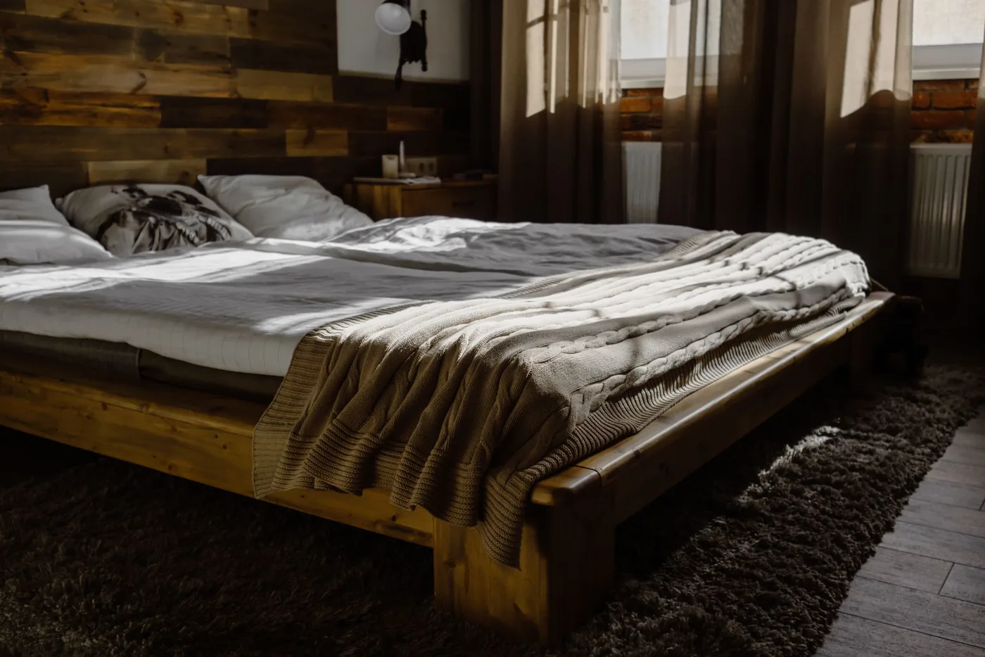 Dřevěná postel s dekami v ložnici