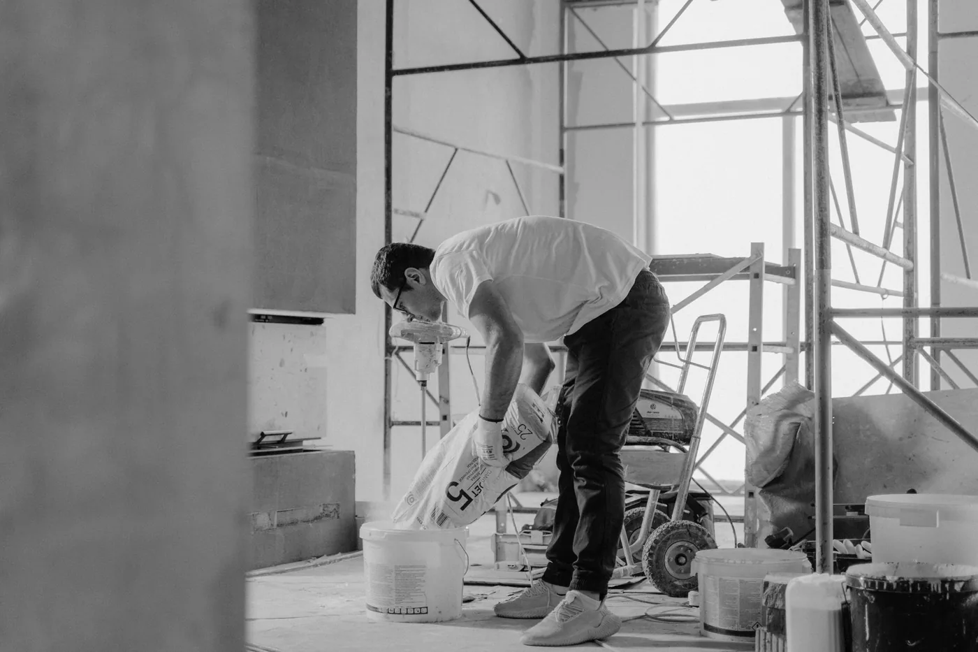 Dělník sype stavební materiál do kbelíku