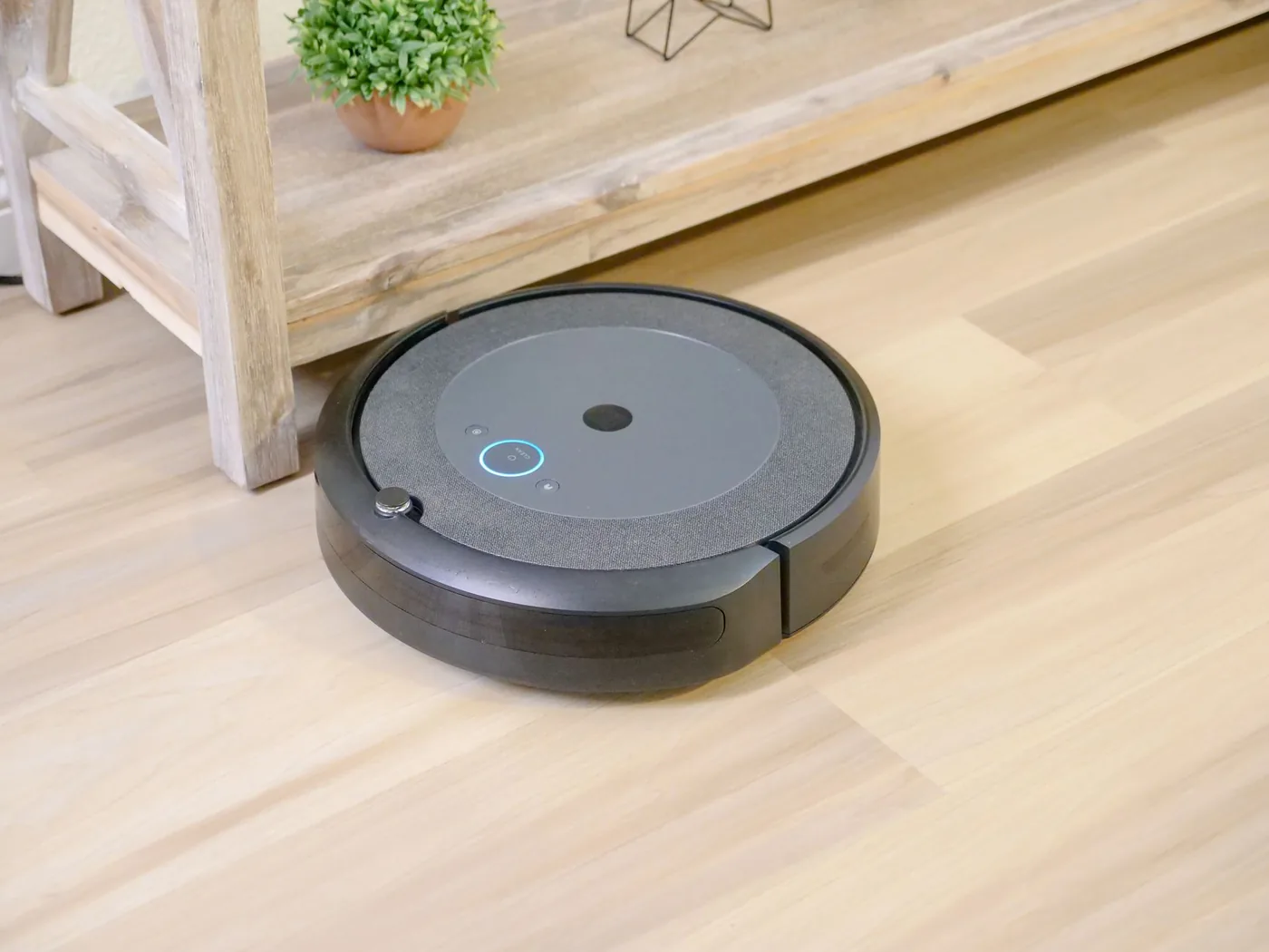 Robotický vysavač jede po dřevěné podlaze