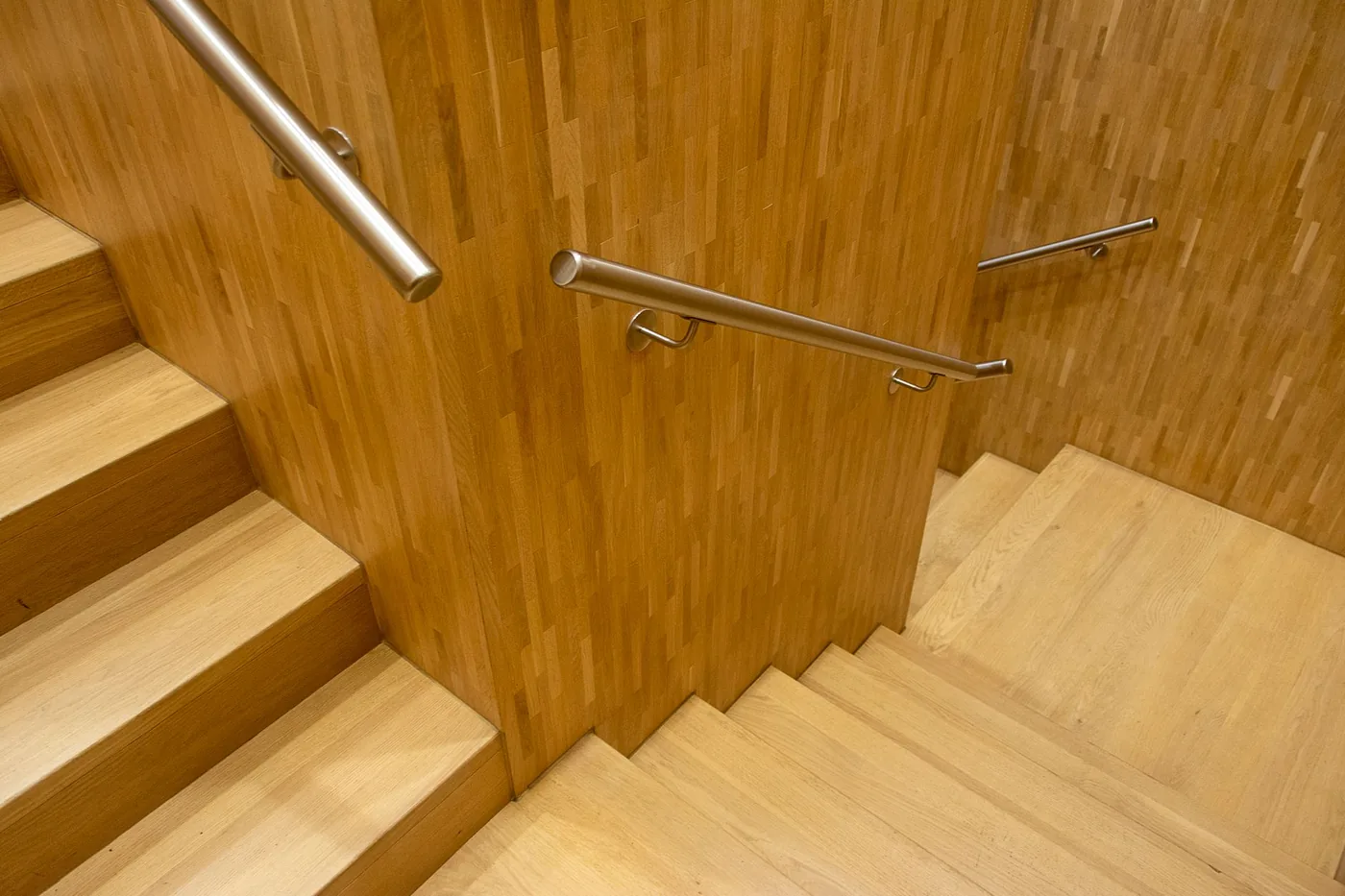 Detail dřevěného schodiště s nerezovým madlem