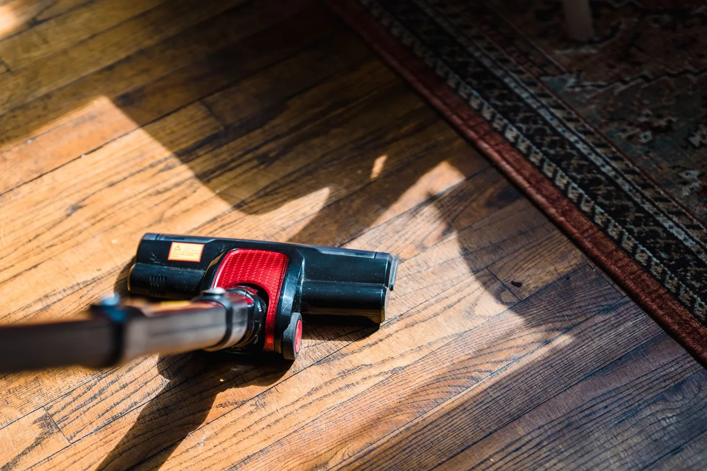 Detail hubice tyčového vysavače na dřevěné podlaze