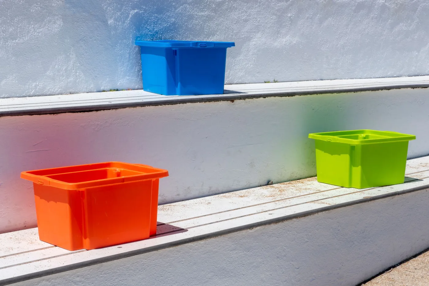 Barevné plastové úložné boxy na venkovních schodech