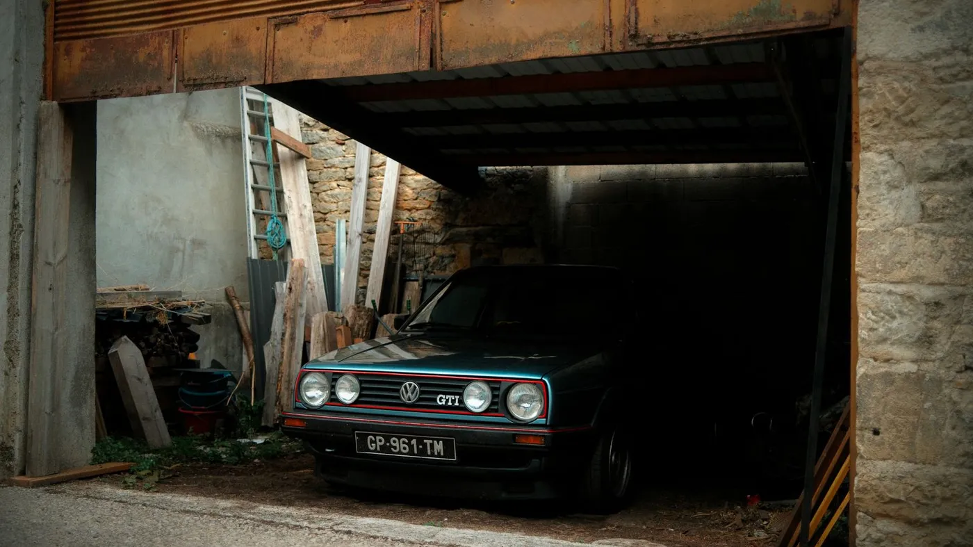 Staré auto stojí v zchátralé garáži, kterou je třeba vyklidit