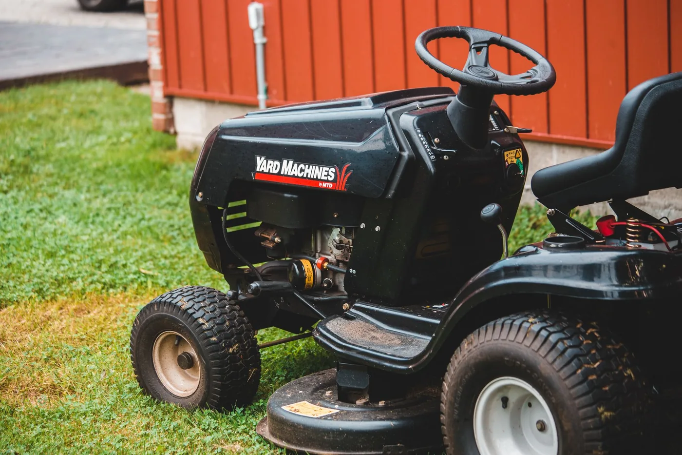 Zaparkovaný jezdecký traktor na trávníku u budovy